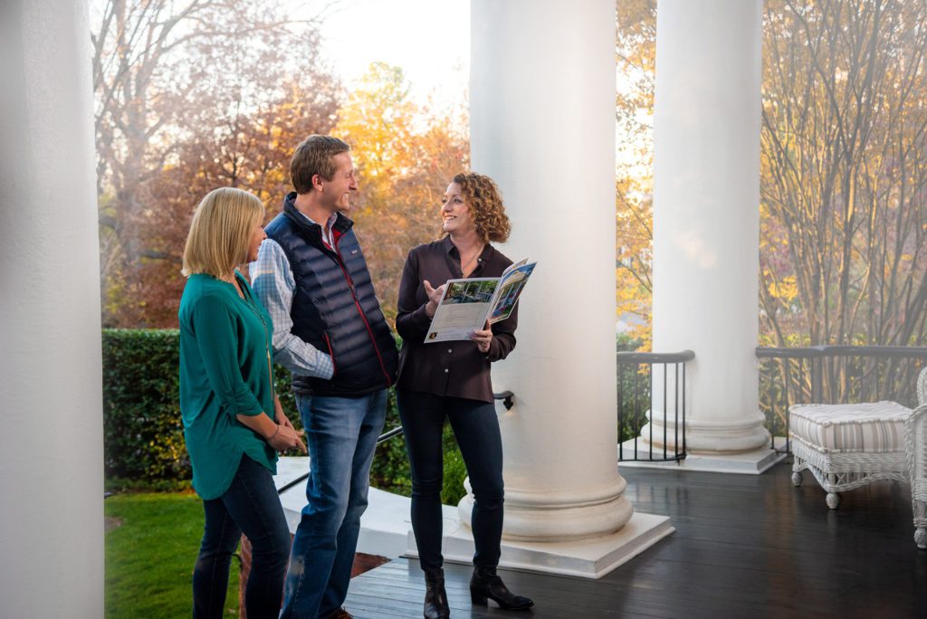 Melissa Greer speaking with clients on the porch of a Greensboro home